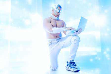 Handsome muscular man of the future wearing futuristic glasses working on a laptop. Technologies of the future.の写真素材
