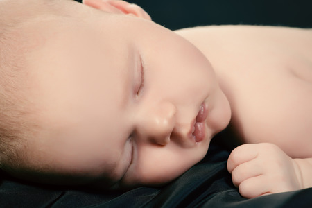 Close-up portrait of a sleeping sweet newborn baby. Over black background.の写真素材