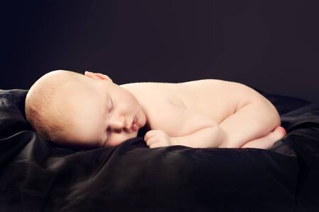 Portrait of a sleeping sweet newborn baby. Over black background.の写真素材