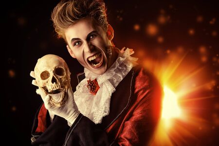 Horrible bloodthirsty vampire holding a skullの写真素材