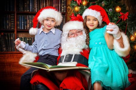 Santa Claus reading fairy tales to children. Christmas scene.の写真素材