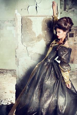 Art Fashion. Beautiful young woman in elegant historical dress and with barocco updo hairstyle posing in the ruins of the castle. Renaissance. Barocco.の写真素材