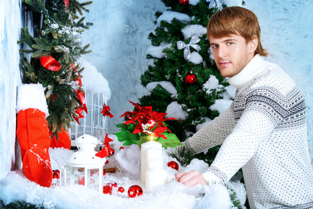Happy young man celebrating winter holidays at home beautifully decorated for Christmas.の写真素材