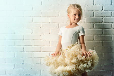 Little girl in a tutu by the white brick wall. Ballet school.の写真素材