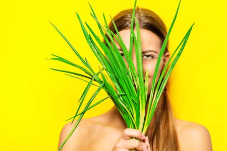 Joyful young woman with green onion over summer yellow background.の写真素材