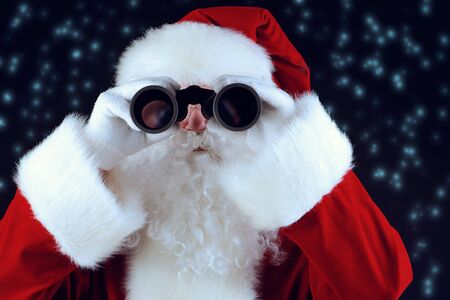 Portrait of Santa Claus looking through the binoculars over black background.の写真素材