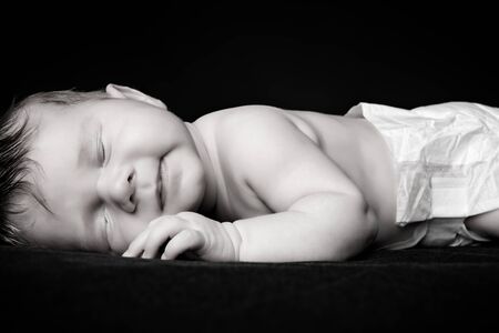 Black-and-white portrait of a little newborn baby asleep. Black background.の写真素材