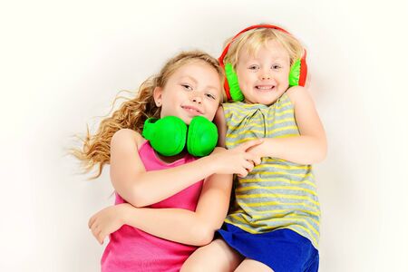 Older and younger sisters listen to music in headphones and laughing. Isolated over white.の写真素材