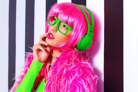 Trendy DJ girl in bright colorful clothes and headphones posing over black-and-white stripes.の写真素材