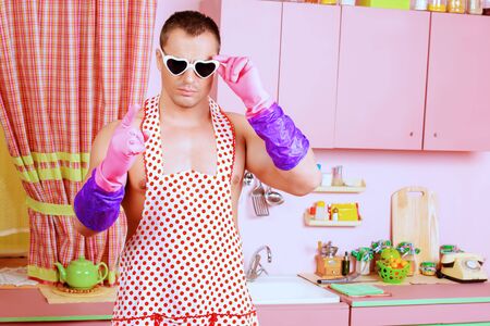 Handsome muscular man in an apron cooking in the pink kitchen.の写真素材