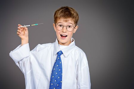Cute funny boy holding a syringe like a doctor. Different occupations. Healthcare.の写真素材