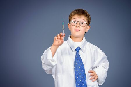 Cute serious boy holding a syringe like a doctor. Different occupations. Healthcare.の写真素材