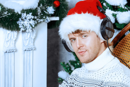 Happy young man celebrating winter holidays at home beautifully decorated for Christmas.