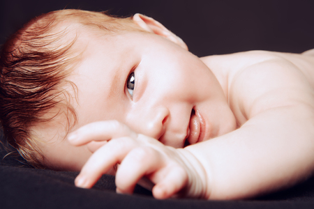 Portrait of a cute little newborn baby. Black background.の写真素材