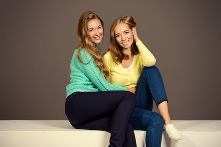 Two beautiful fashion models posing at studio in bright casual clothes. Beauty, fashion.の写真素材