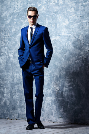 Full length portrait of a fashionable handsome young man in elegant classic suit and sunglasses.の写真素材