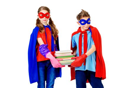 Boy and girl teenagers in a costume of superheroes holding books. Isolated over white background.の写真素材