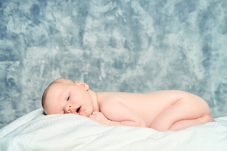 Cute newborn baby sleeps peacefully on a soft white blanket.の写真素材