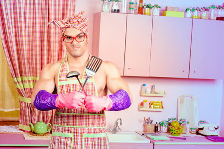 Attractive muscular man in an apron posing with a ladle with expression. Family, love concept. Valentine's day. Women's day.の写真素材