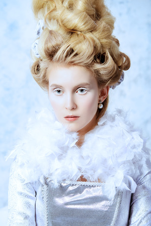 Beautiful young lady in a historical dress and high hairdo in a Renaissance style. Vintage fashion. Elegant Ice Queen over frozen background..の写真素材