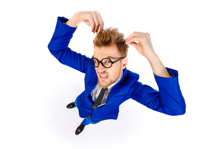 Funny smart guy in a suit and spectacles looking at camera and touching his hair. Isolated over...