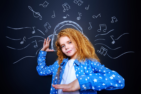 Cheerful little girl enjoys the music in headphones. Studio shot.の写真素材