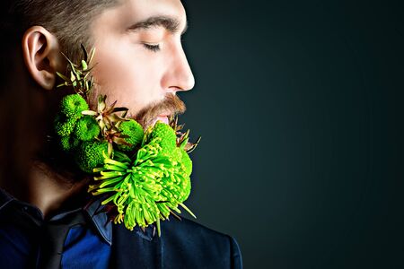 Profile of a handsome man with a beard of green flowers. Men's beauty. Barbershop.の写真素材