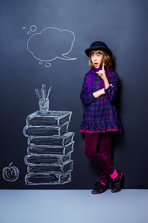 Educational concept. Teen girl standing by the background of the school board with drawn stack of books.の写真素材