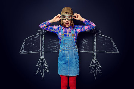 Dream flight. Cheerful girl imagines herself a pilot. Childhood. Fantasy, imagination.