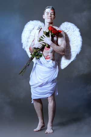 Inspired, romantic man-angel with red rose. Cupid. Valentine's day. Love concept.の写真素材