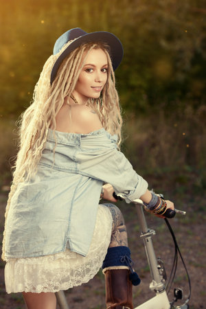 Carefree smiling girl in boho style clothes rides a bicycle.の写真素材