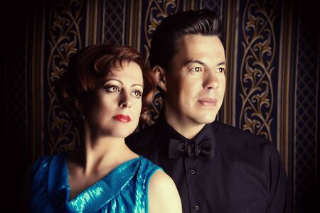 Portrait of a beautiful mature man and woman in evening clothes over vintage background.の写真素材