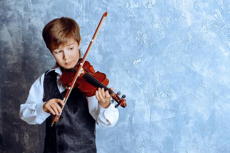 Freckled nine year old boy playing the violin. Musical education. Inspiration.の写真素材