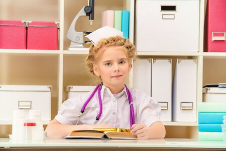 Pretty little girl playing a doctor at home. Different occupations. Children's Health, Pediatrics.の写真素材