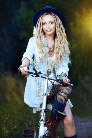 Carefree smiling girl in boho style clothes rides a bicycle. Beauty, fashion. Summertime.の写真素材