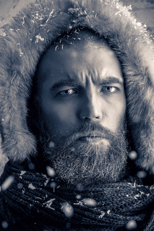 Black-and-white portrait of a brutal man with beard and mustache dressed in winter clothes, covered with frost.の写真素材