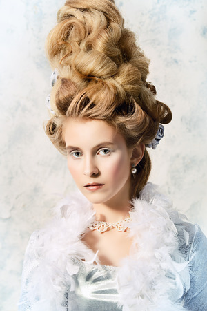 Beautiful young lady in a historical dress and high hairdo in a Renaissance style. Vintage fashion. Elegant Ice Queen over frozen background..の写真素材