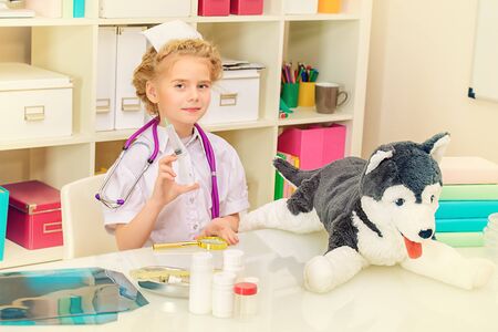 Pretty little girl playing a doctor at home. Different occupations. Children's Health, Pediatrics.の写真素材
