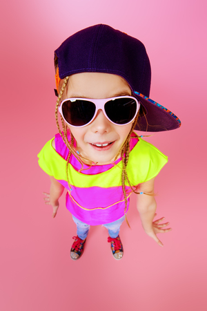 Trendy little girl in a cap smiling to camera. Kid's fashion. Happy childhood.の写真素材