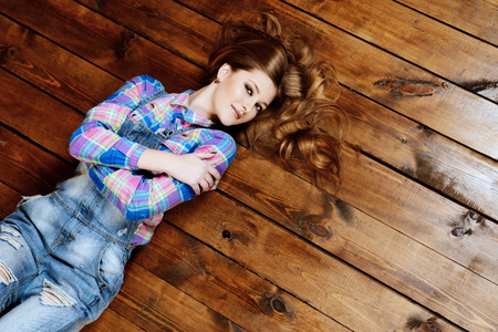 Young woman in casual jeans clothes lying on a wooden floor. Youth style. Copy space.の写真素材