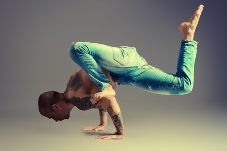 A man doing yoga exercises. Studio shot over gray background.