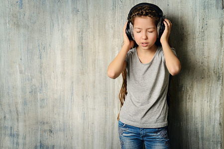 Cool teen girl enjoys the music in headphones. Studio shot.の写真素材