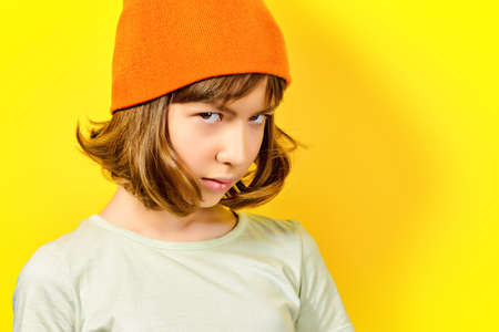 Portrait of a thoughtful and a little bit sad teen girl over yellow background.の写真素材