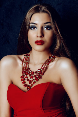 Beautiful woman with evening make-up and magnificent long hair wearing red dress.の写真素材