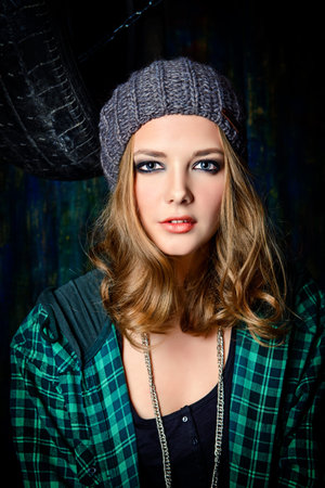 Portrait of a modern teenager girl wearing street clothes sitting in the old garage. Grunge style.の写真素材