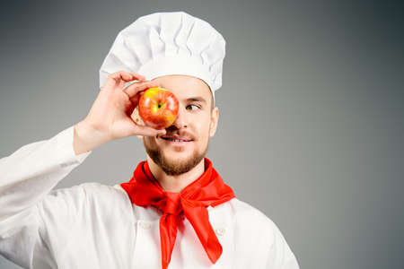 Closeup portrait of a funny male cook holding an apple.の写真素材