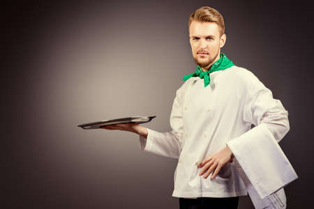 Portrait of a male chef cook in uniform holding empty tray. Copy space. Occupation. Studio shot.の写真素材