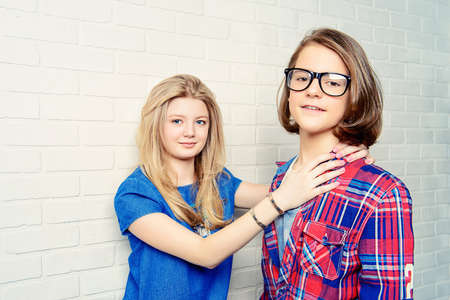 Two modern teenage boy and girl standing together by a brick wall. Friendship. First love.の写真素材