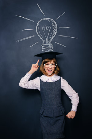Educational concept. Smiling schoolgirl standing by a blackboard. New idea. Copy space.