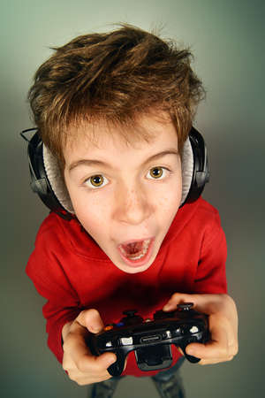 Funny boy gamer with a controller and headphones. Studio shot.の写真素材
